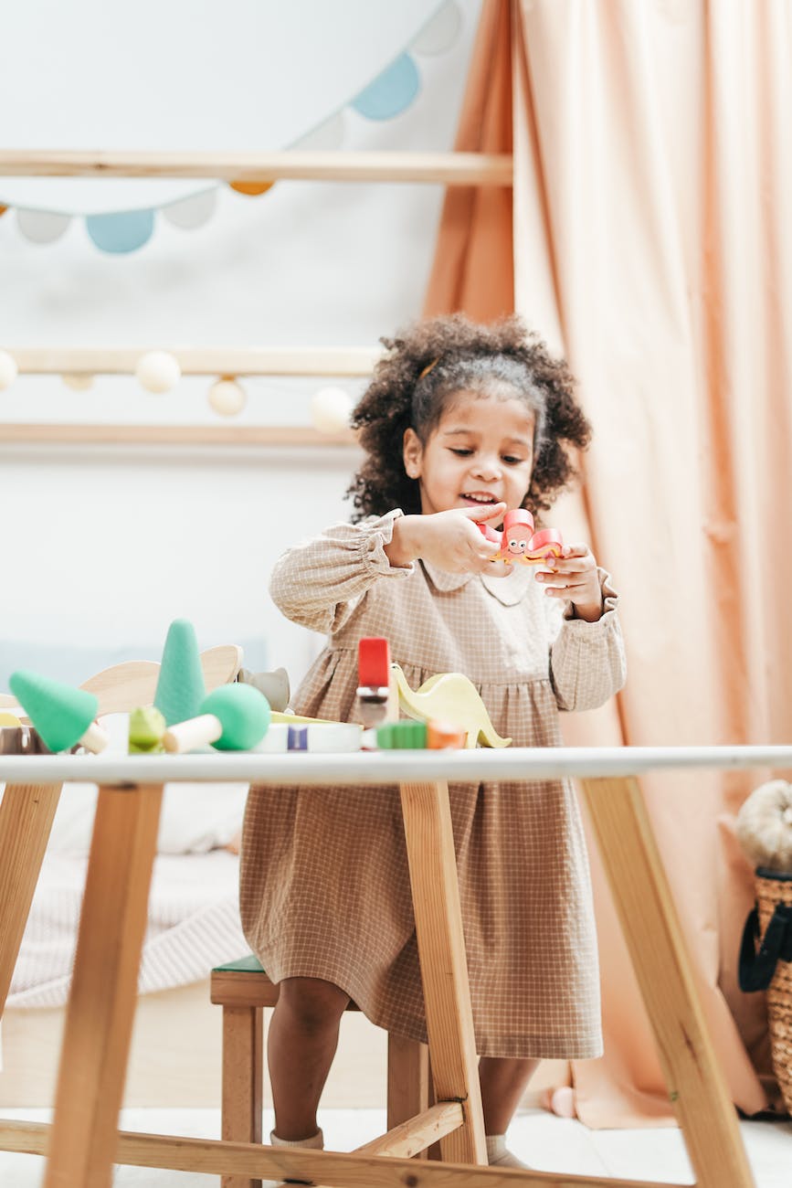 girl holding a pink colored wooden toy